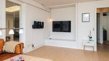 Ein modernes Wohnzimmer mit Fernseher, Holzboden, einer Couch, einem Couchtisch und einem kleinen Beistelltisch mit einer Pflanze.