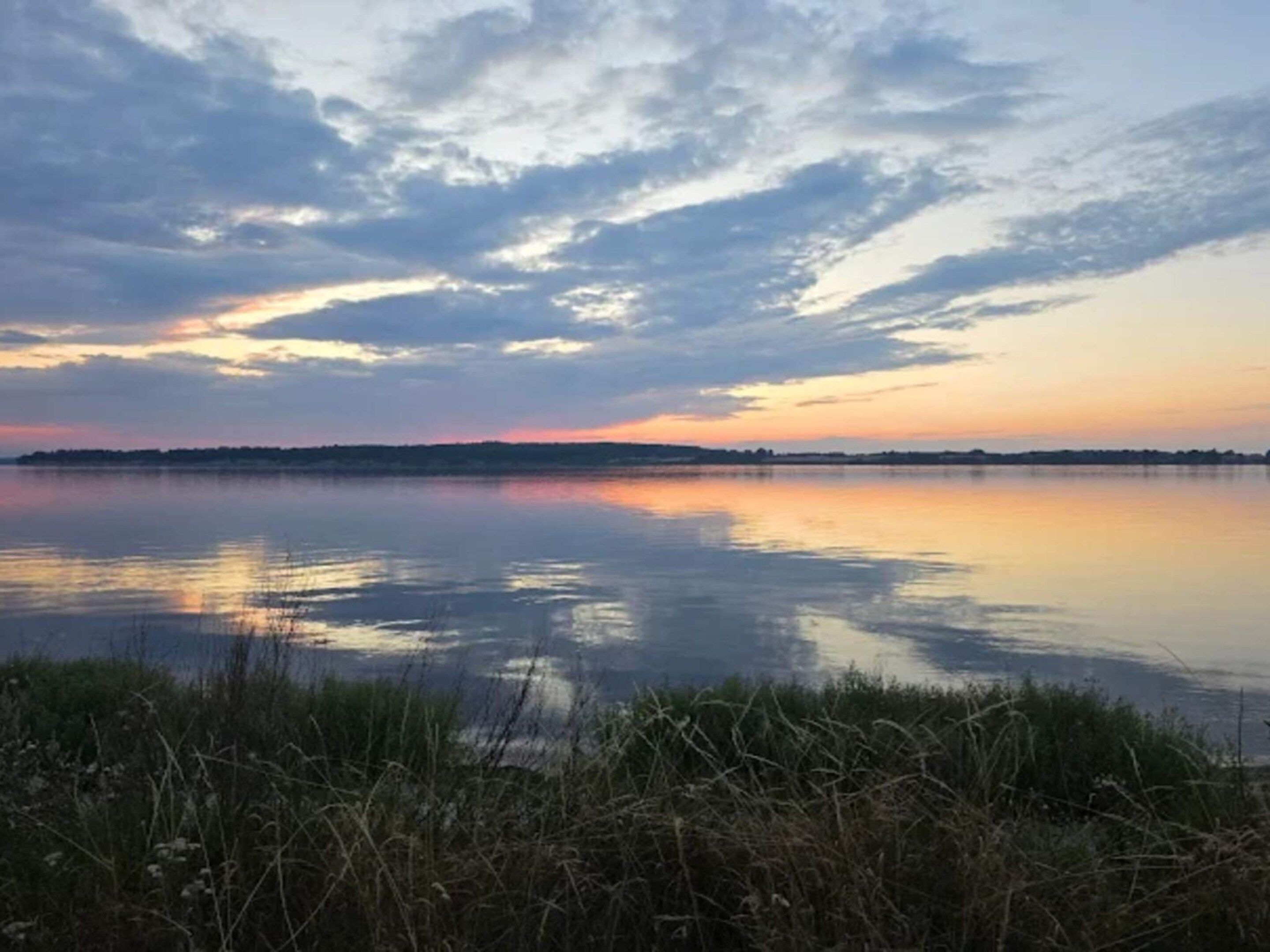 Un lago tranquilo con cielo despejado y horizonte lejano.