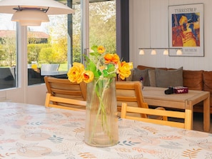A room with a dining table, a vase with flowers, a sofa, and a painting on the wall. - 6 Person Holiday Home in Sydals-by Traum (Sydals)