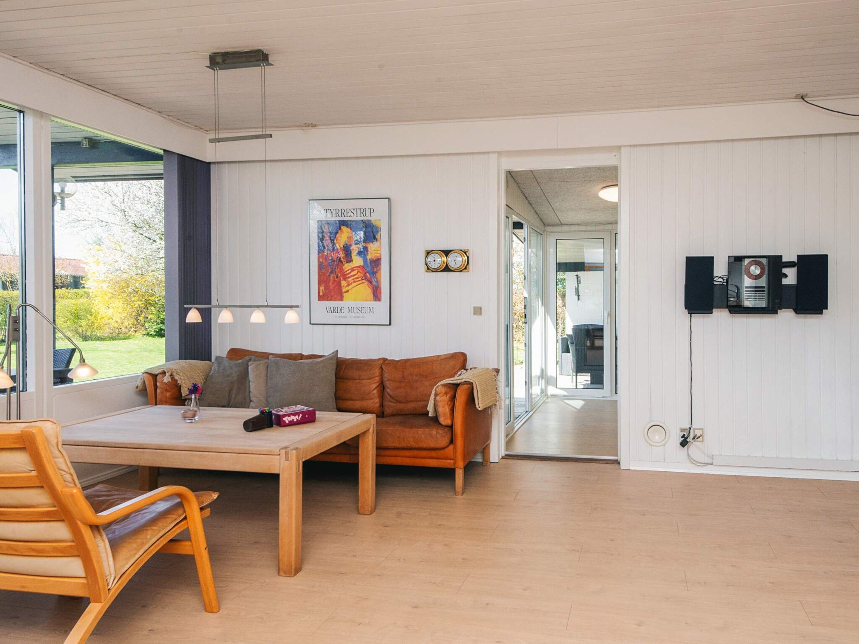 Un interior moderno con una mesa de madera, un sofá marrón y un cartel en la pared.