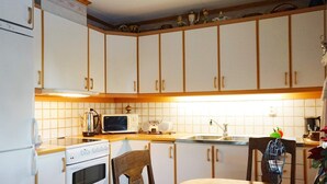 A kitchen with white cabinets, a microwave, an oven, and a dining table with a blue tablecloth. - 4 Star Holiday Home in Bullaren (Bullaren)