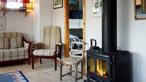 A cozy living room with a fireplace, a sofa, a chair, and a small table. - 4 Star Holiday Home in Bullaren (Bullaren)