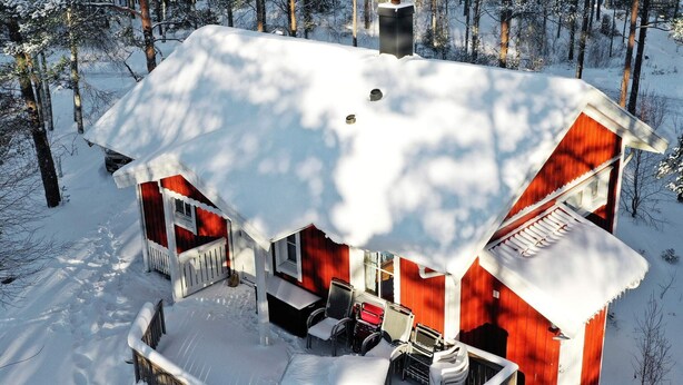 A wooden cabin with a snow-covered roof and a deck area with outdoor furniture. - 4 Star Holiday Home in Bullaren (Bullaren)