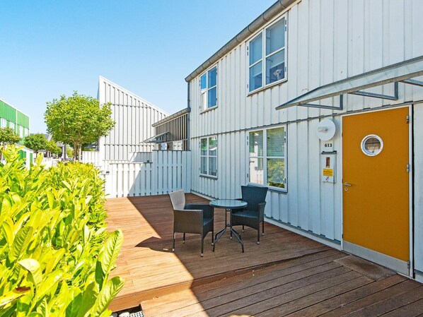 A modern building with a wooden deck, outdoor seating, and a yellow door. - 4 Star Holiday Home in Ebeltoft (Ebeltoft)