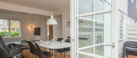Un comedor moderno con una mesa blanca, sillas negras y un ventanal grande.