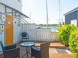 A deck with two wicker chairs and a glass table, overlooking a marina with boats.