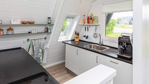 Una cocina moderna con encimera negra, armarios blancos y una ventana con vistas al exterior.