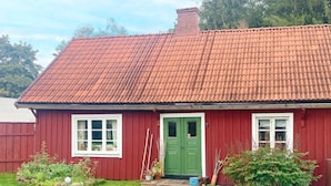 Een rode houten woning met een groene deur, witte ramen en een pannendak.