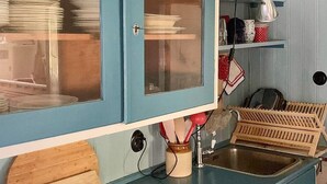 Een keuken met een blauwe kast, een spoelbak en een houten snijplank.
