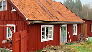 Een rode houten woning met een schuin dak en schoorsteen.