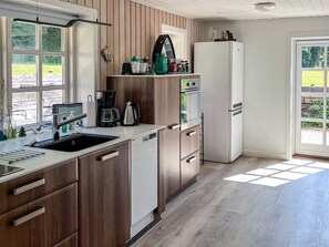 A modern kitchen with wooden cabinets, a built-in oven, a coffee maker, and a refrigerator. - 4 Person Holiday Home in Hanstholm (Hanstholm)