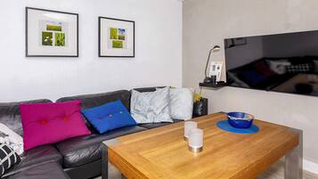 Una sala de estar moderna con un sofá de cuero, una mesa de centro de madera y dos cuadros en la pared.