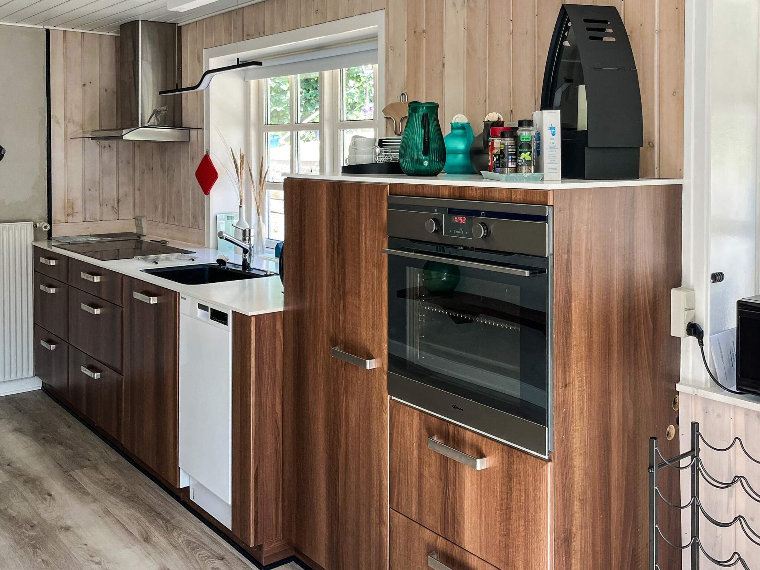 A modern kitchen with wooden cabinets, a stainless steel oven, and a dishwasher.