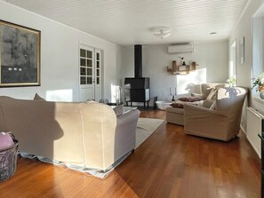 A living room with a sofa, armchairs, a fireplace, and a large painting on the wall. - 4 Star Holiday Home in Nosund (Nosund)