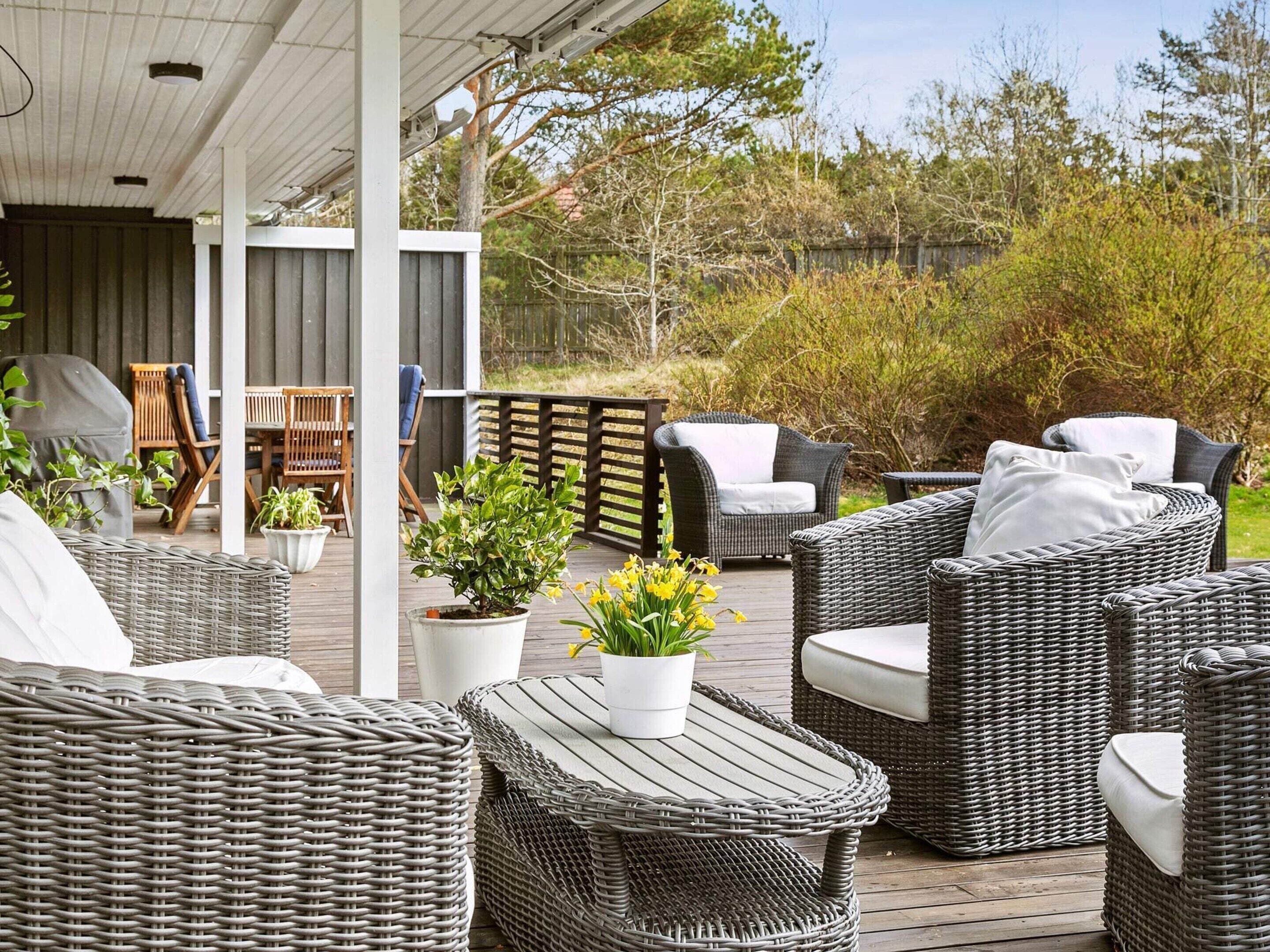 A covered outdoor seating area with wicker furniture and potted plants.