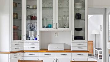 A kitchen with white cabinets, a wooden countertop, and a dining area with two wooden chairs.