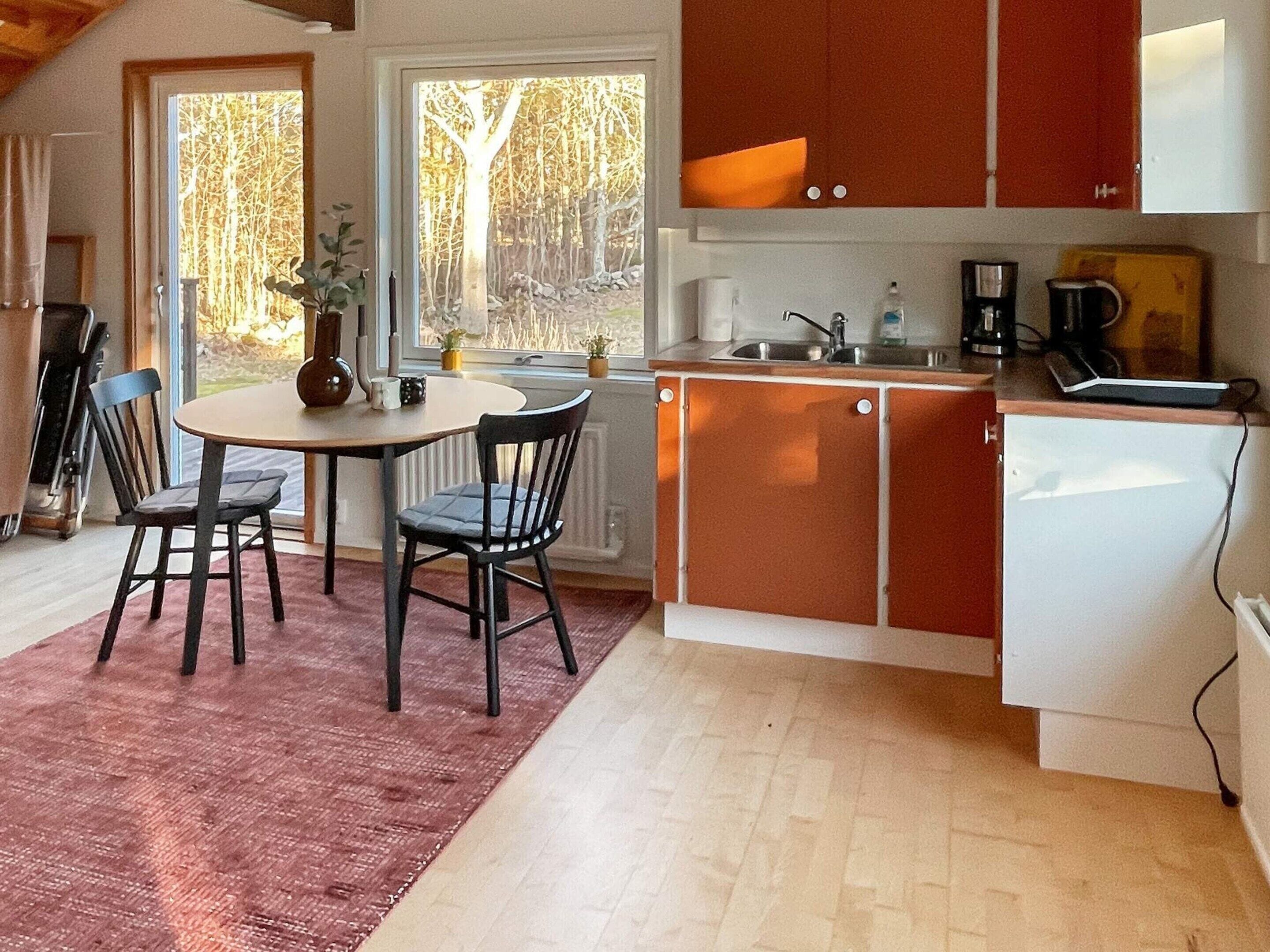 A compact kitchen with a dining area, a refrigerator, and a coffee maker.