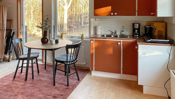 A compact kitchen with a dining area, a refrigerator, and a coffee maker. - 12 Person Holiday Home in Nosund-by Traum (Nosund)