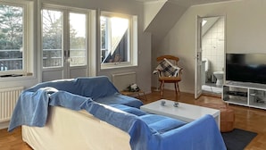 A living room with a sofa, a coffee table, a television, and a chair. - 12 Person Holiday Home in Nosund-by Traum (Nosund)