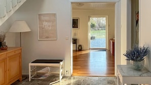 A hallway with a bench, a lamp, a framed picture, and a door leading to a room with a view of the outdoors. - 12 Person Holiday Home in Nosund-by Traum (Nosund)