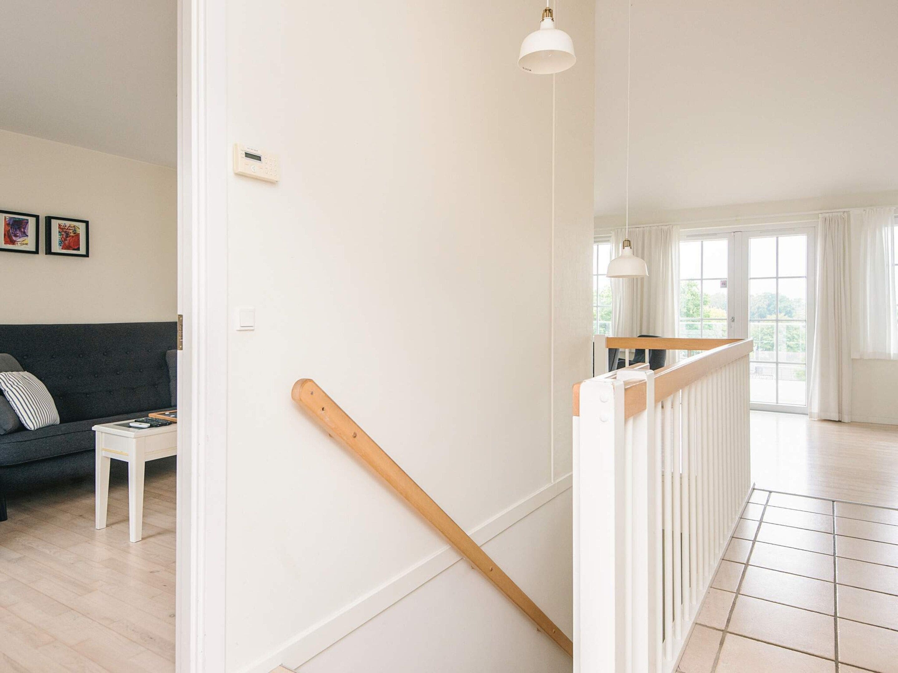 Un interior moderno con una escalera, un sofá y vistas al exterior.