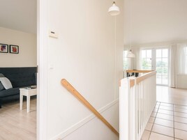 Un interior moderno con una escalera, un sofá y vistas al exterior.