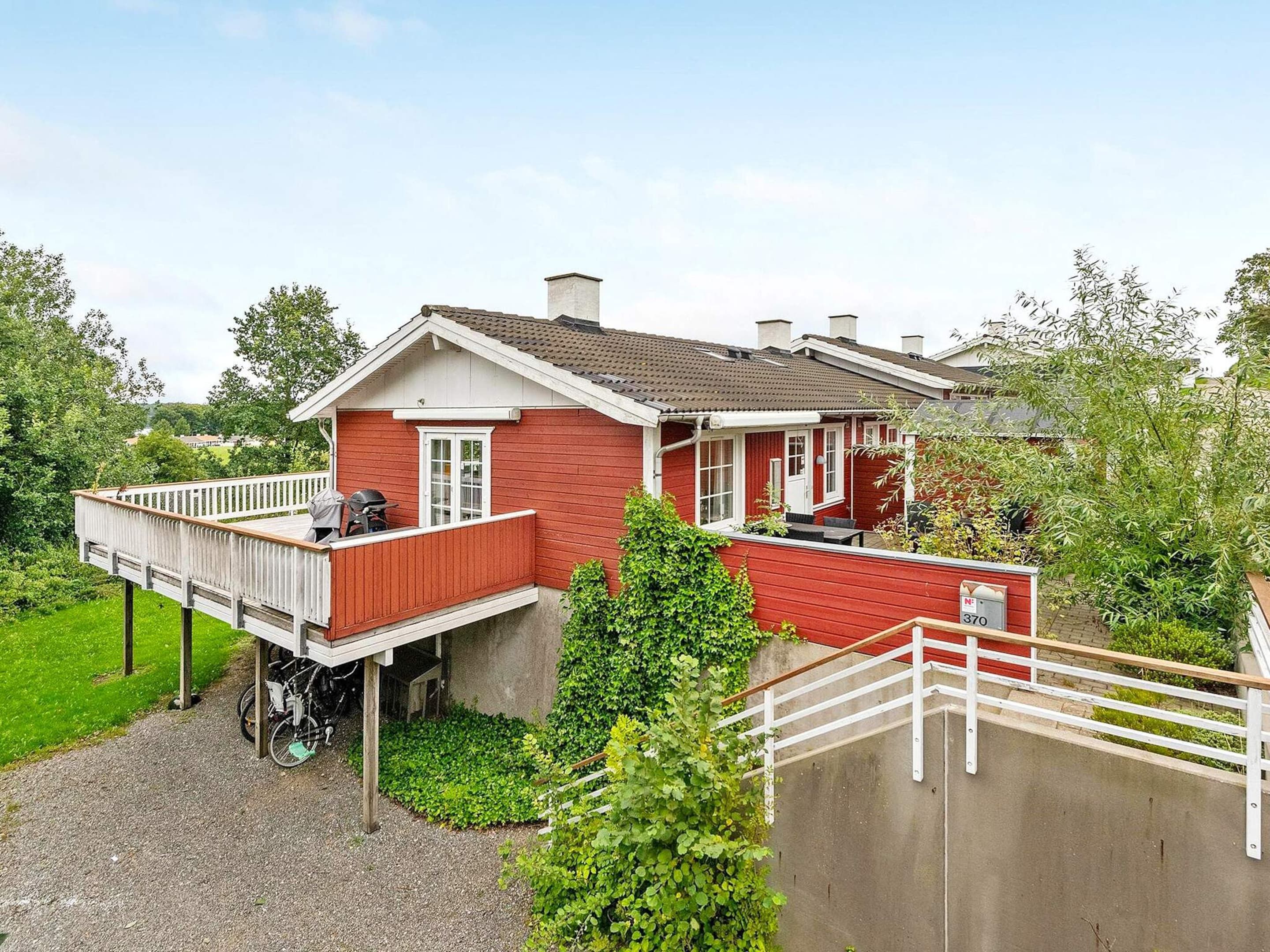 A red house with a balcony, a garage, and a garden.