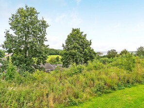 A rural landscape with trees, a house, and a view of the sea. - 6 Person Holiday Home in Aabenraa (Aabenraa)
