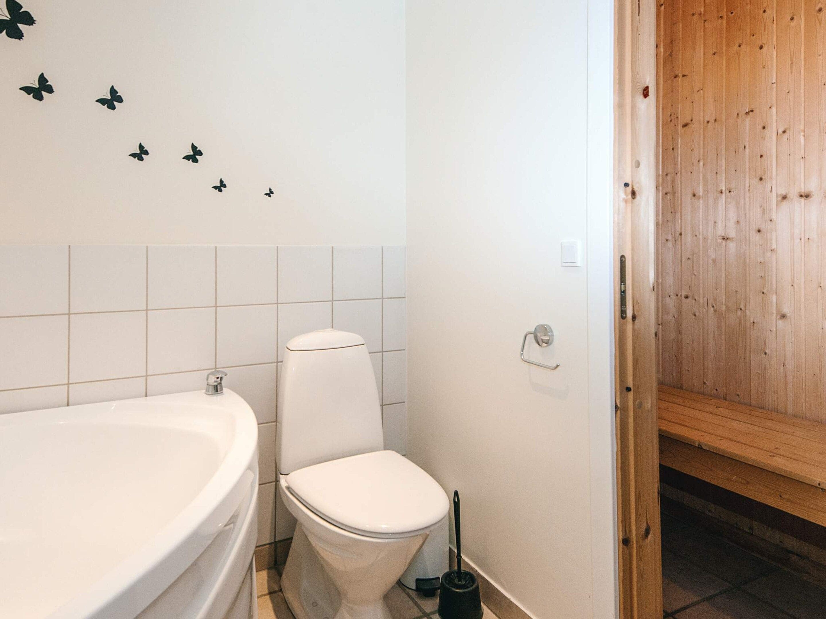 Un bagno con una vasca da bagno bianca, il water e una porta in legno che dà su un'altra stanza.