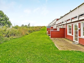 A row of red wooden houses with white trim, a paved pathway, and a grassy area.