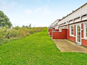 A row of red wooden houses with white trim, a paved pathway, and a grassy area. - 6 Person Holiday Home in Aabenraa (Aabenraa)