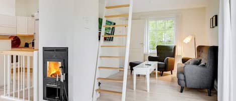 Un intérieur moderne avec une cheminée, un escalier en bois, un coin salon et une cuisine.