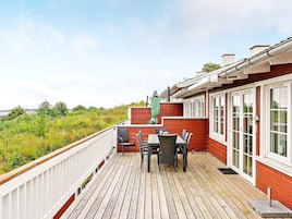 Una terraza de madera con una mesa y sillas, con vistas a un paisaje natural.