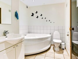 Et badeværelse med badekar, toilet og håndvask.