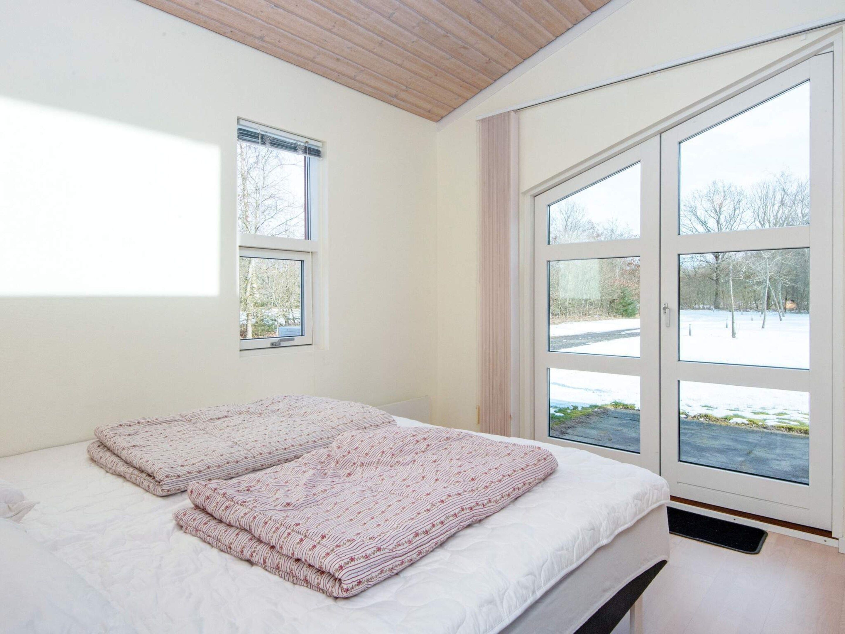 A bedroom with a bed, a window, and a view of a snowy landscape.