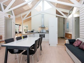 A modern kitchen with white cabinets, a microwave, and a stove. There is a dining area with a table and chairs. - 6 Person Holiday Home in Vemb-by Traum (Vemb)
