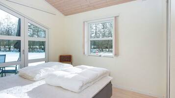 A bedroom with a bed, a chair, and a window.