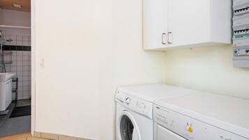 A laundry room with a washing machine, a dryer, and electrical panels.