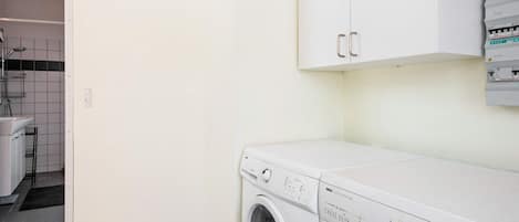 A laundry area with a washing machine, a dryer, and electrical panels on the wall.