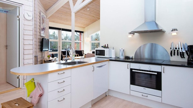 A modern kitchen with white cabinetry, a stainless steel range hood, and a built-in oven.