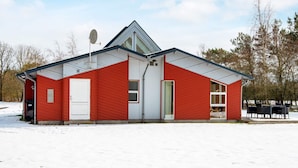 A red building with a white garage door, a satellite dish, and a covered outdoor seating area.