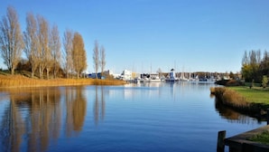 Un lac paisible, avec des bateaux, un quai et des bâtiments en arrière-plan.