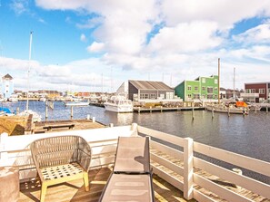 A marina with boats docked, a wooden deck with seating, and buildings along the water. - 6 Person Holiday Home in Ebeltoft (Ebeltoft)