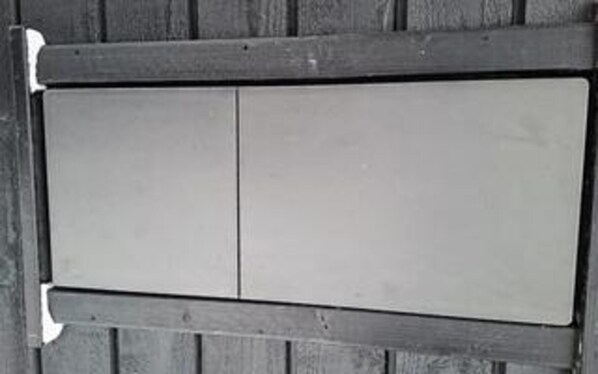 A wooden panel with a white rectangular sign attached to it.