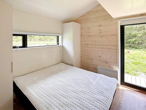 Une chambre à coucher avec un lit, une fenêtre et une vue sur la verdure.