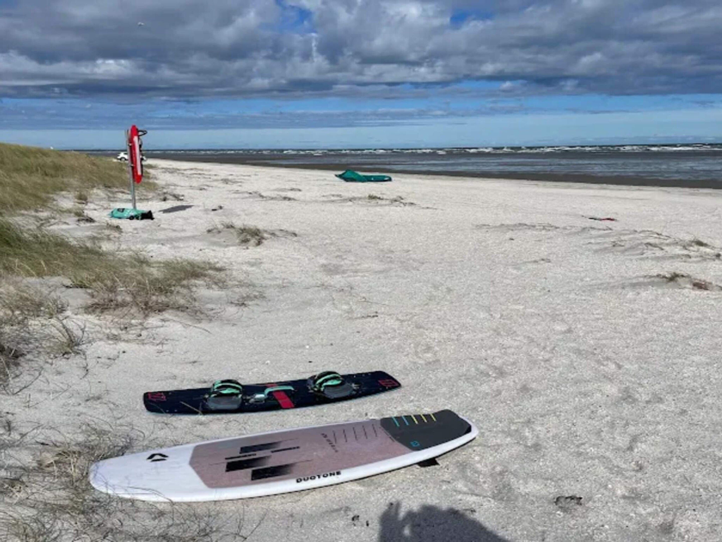 Une plage de sable avec une planche de surf et un drapeau rouge sur la gauche.