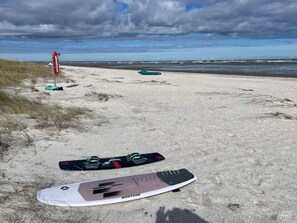 Une plage de sable avec une planche de surf et un drapeau rouge sur la gauche.