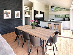 A modern kitchen with a central island, pendant lighting, and a dining area with a wooden table and chairs. - 7 Person Holiday Home in Jerup-by Traum (Jerup)
