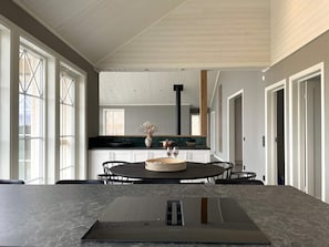 A modern kitchen with a central island, white cabinetry, and a large window.
