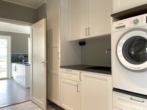 A compact kitchen with white cabinets, a built-in washing machine, and a small countertop.
